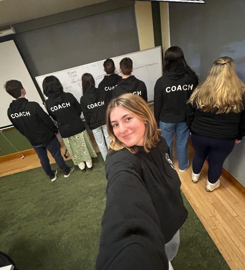 A group of students pose for a picture wearing their new black hoodie sweatshirts.