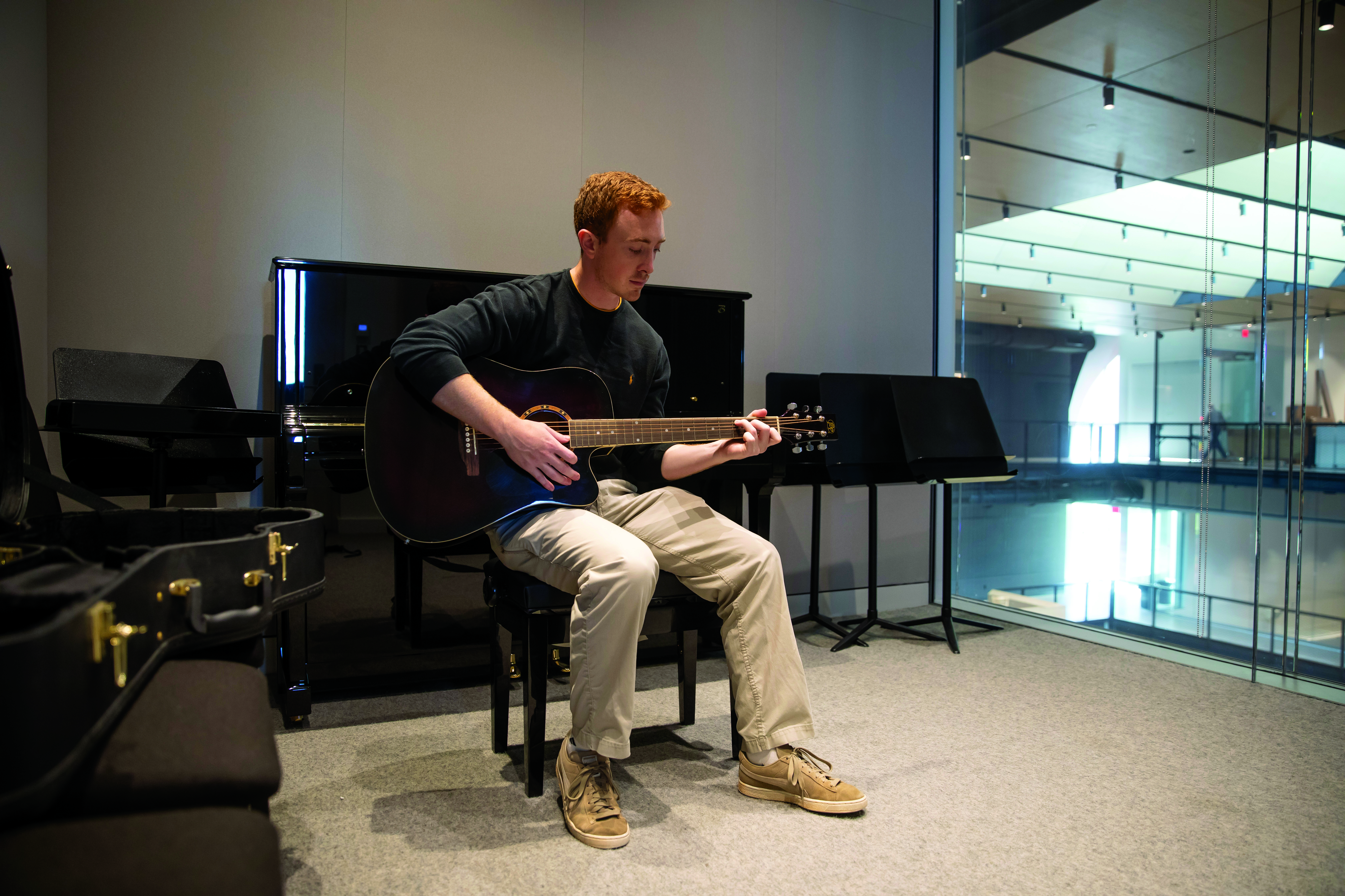 A students plays guitar in a solo studio.