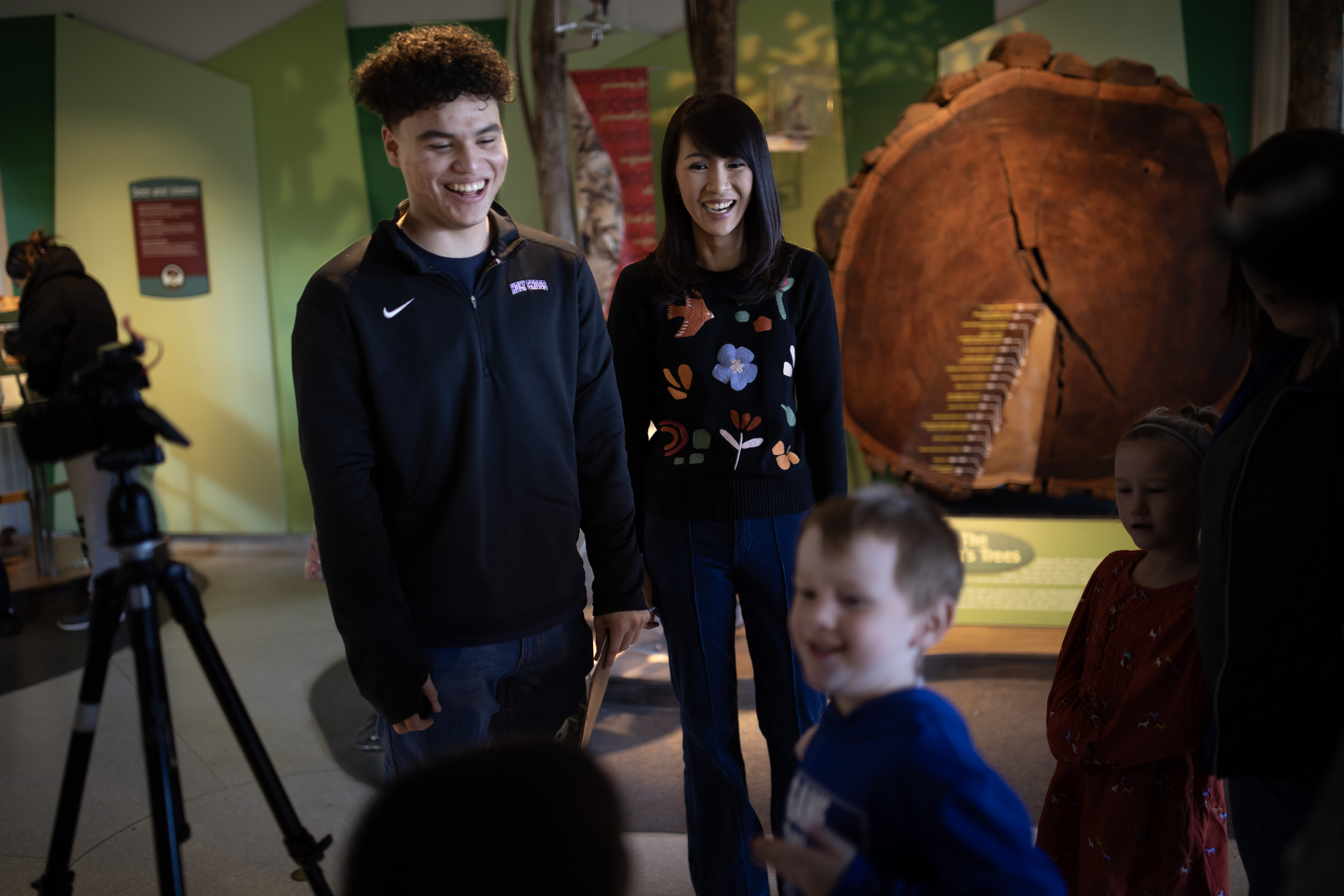 Male student and female professor laugh with a small boy at a museum.