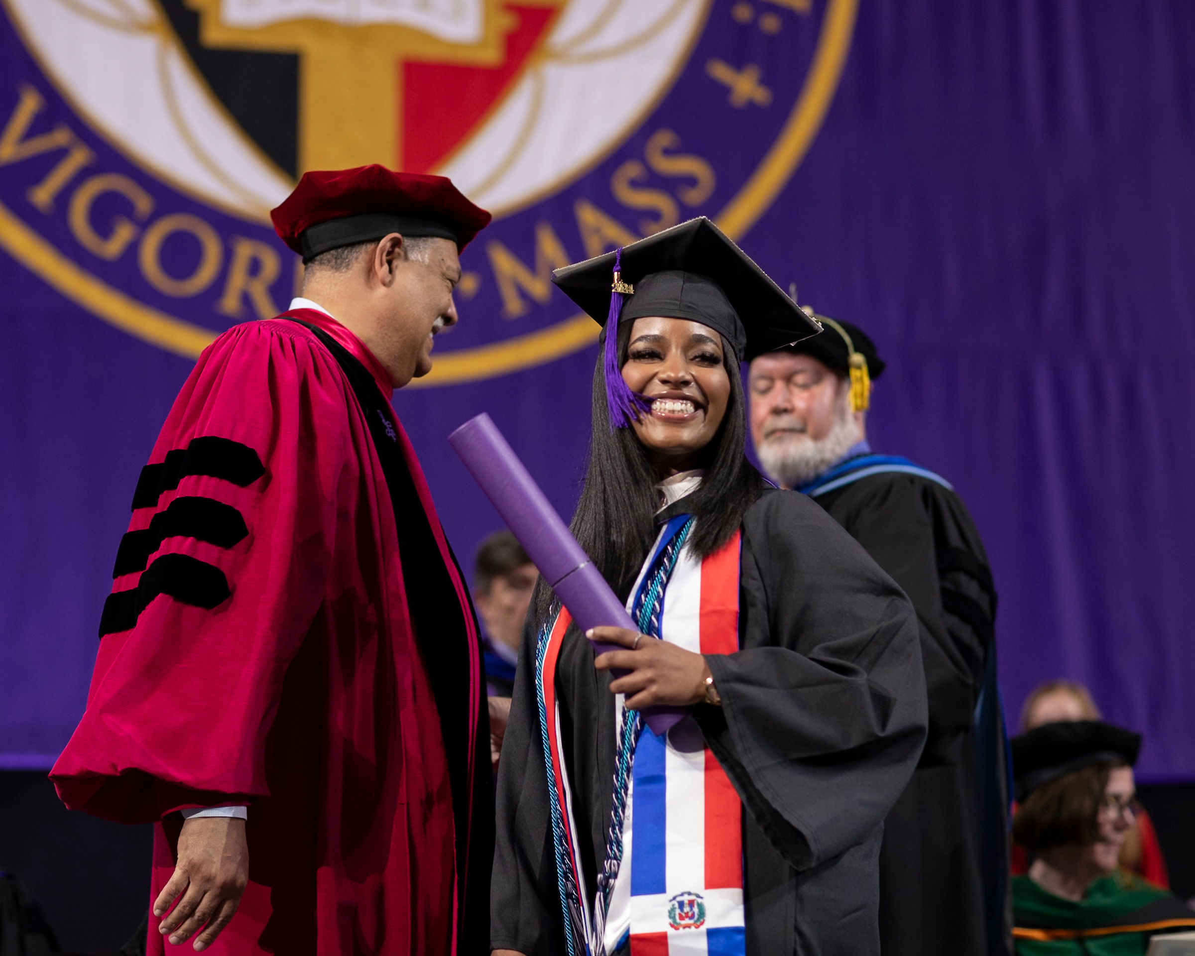 Female student receives her college diploma from a college president during a commencement ceremony.