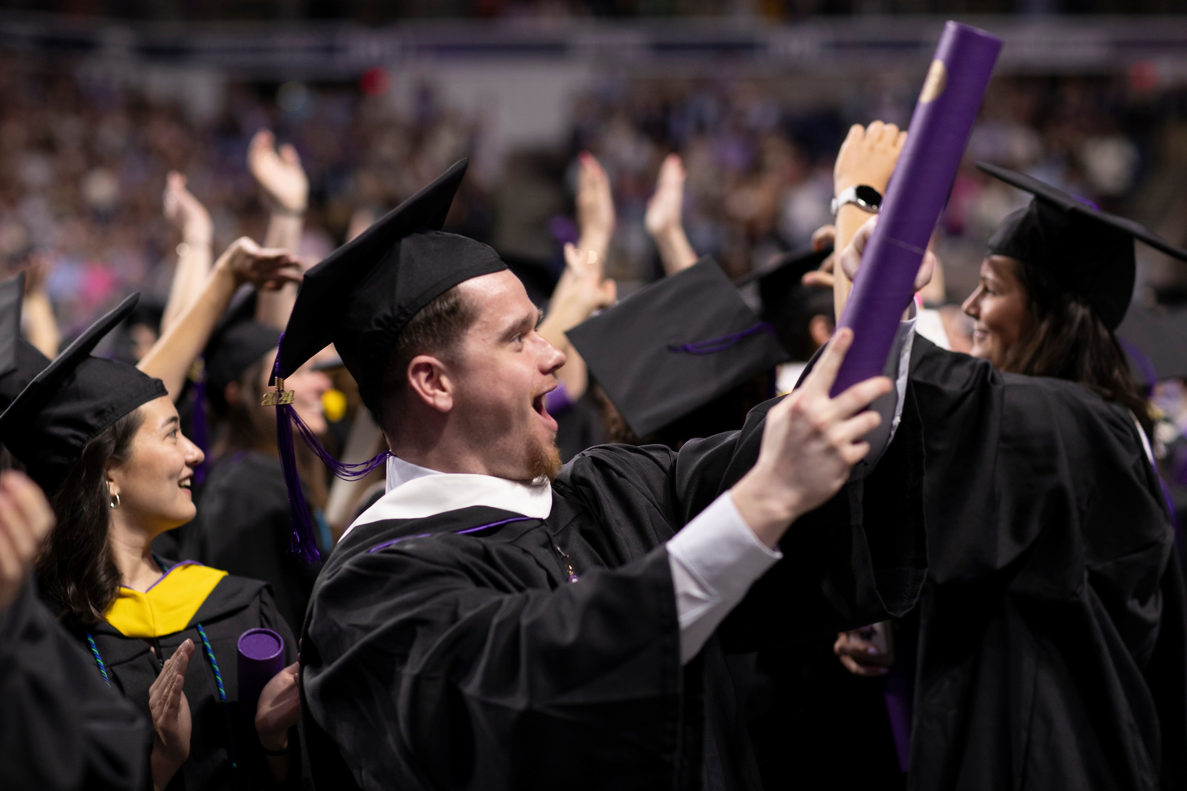 Male college student cheering during commencement ceremony.