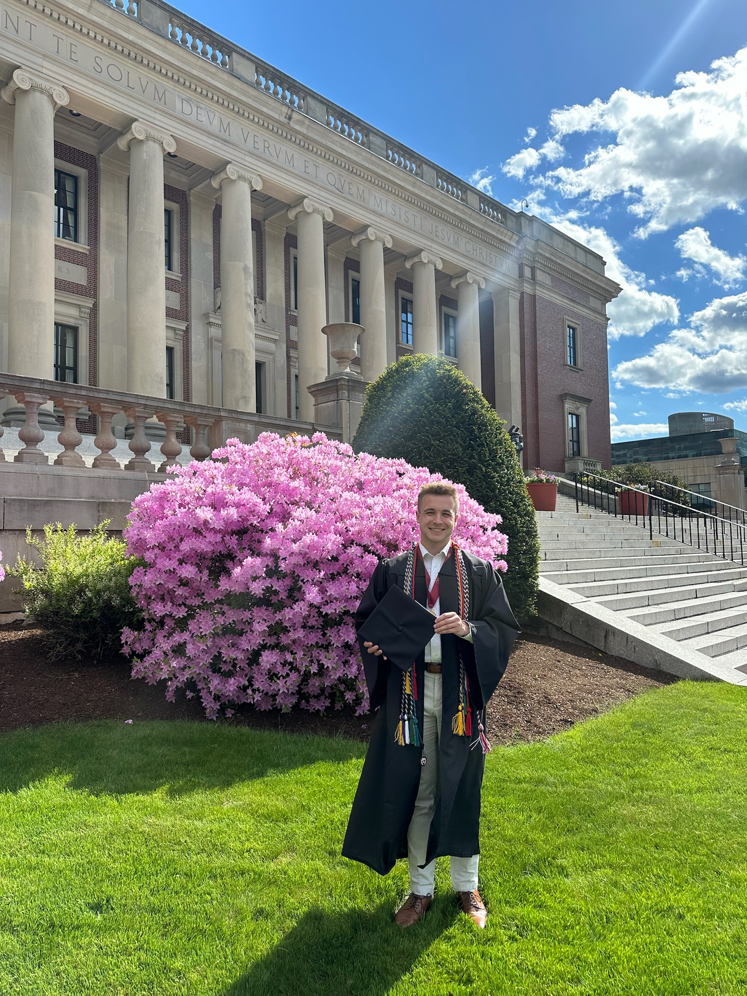 Kevin Hamilton outside Dinand Library in a cap and gown