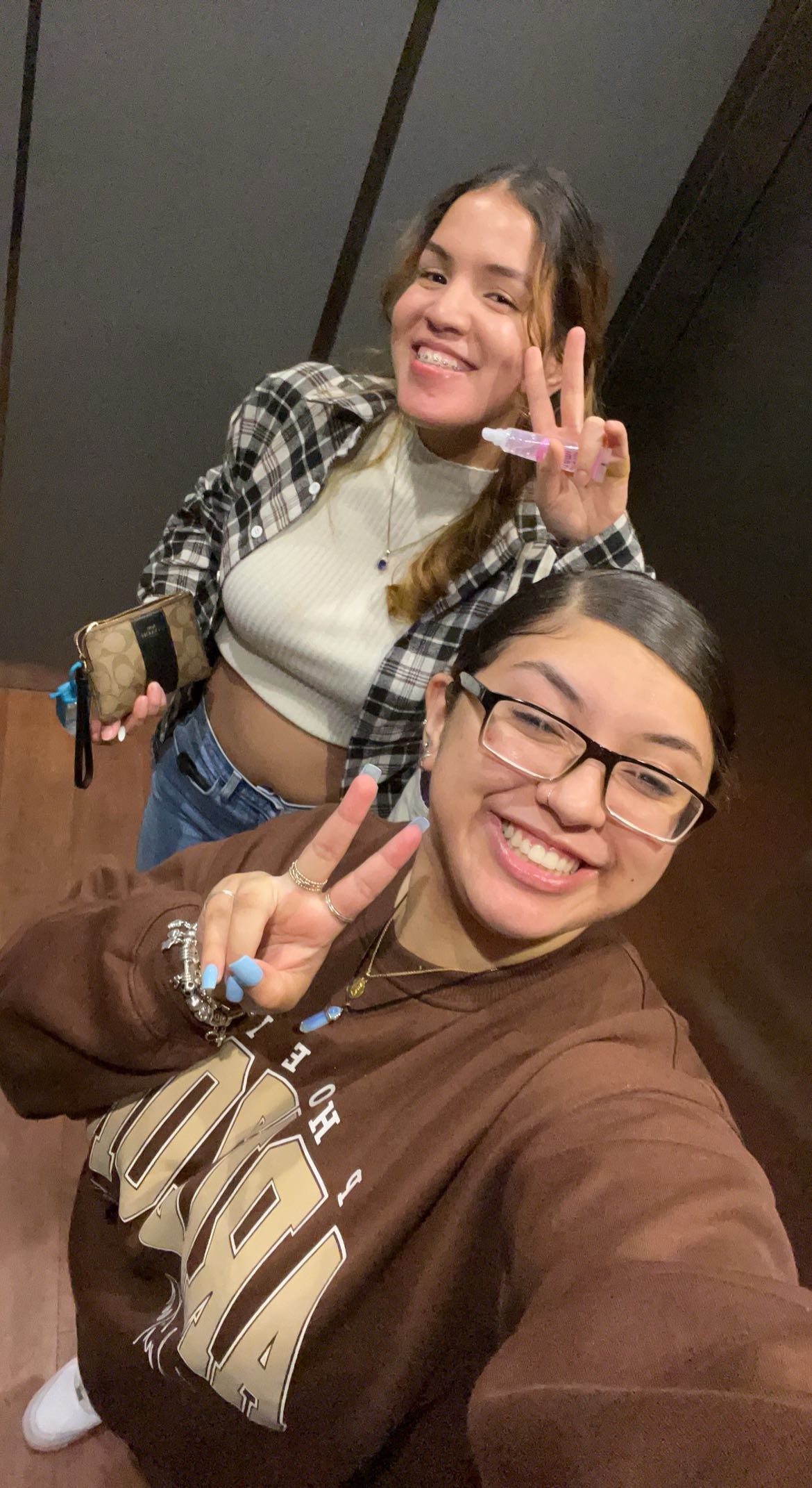 Two young woman taking a selfie and holding up two fingers