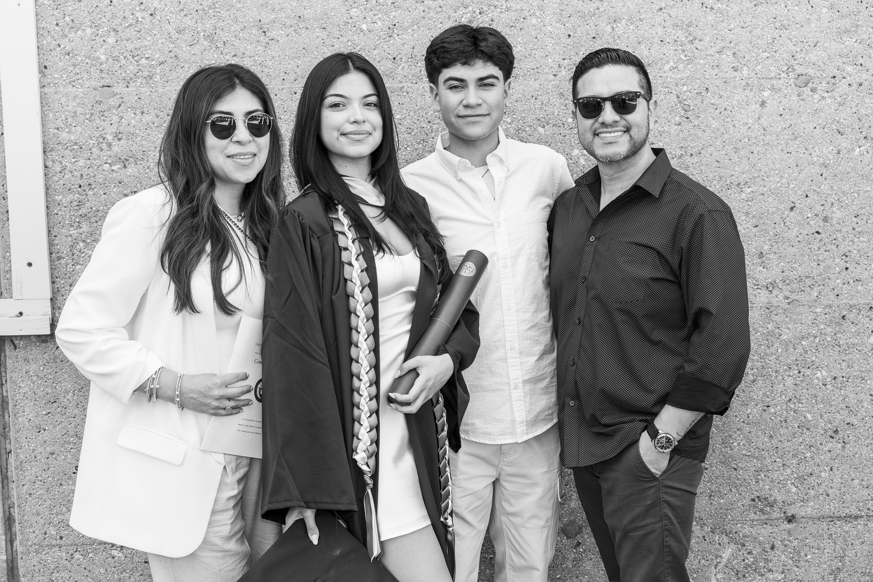 A family poses together with a college graduate