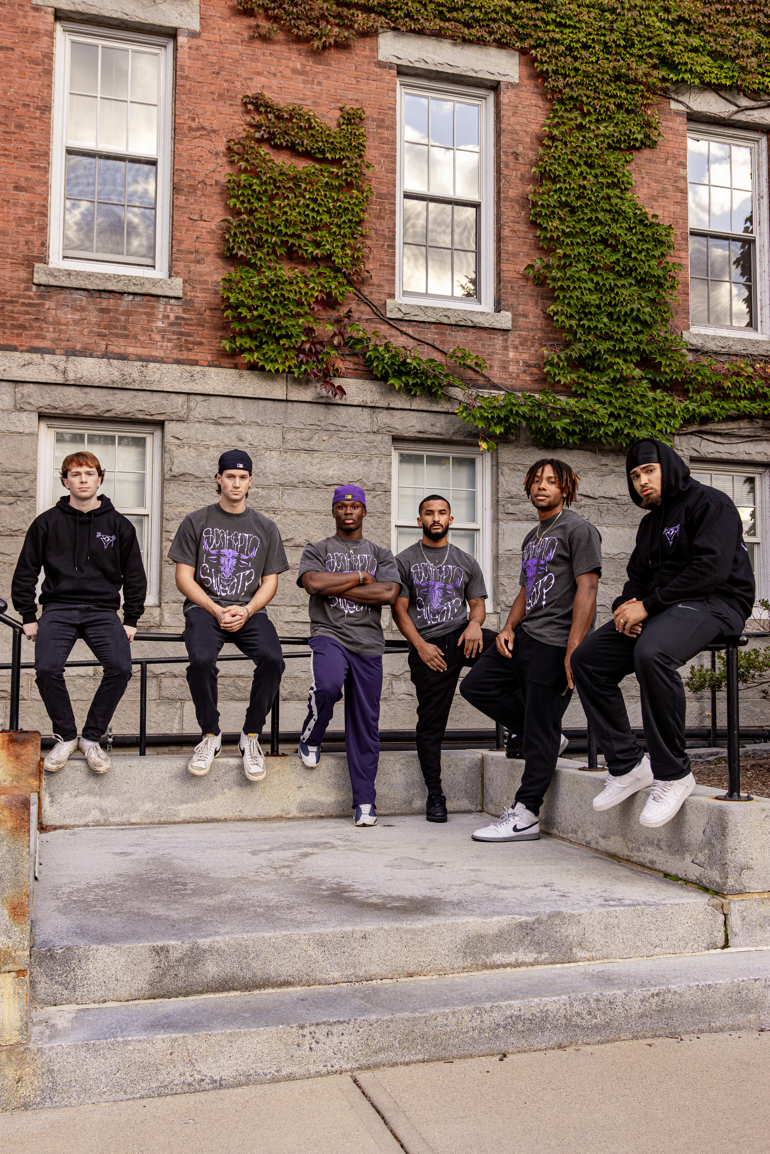 A group of young men sitting on a railing outside a brick building