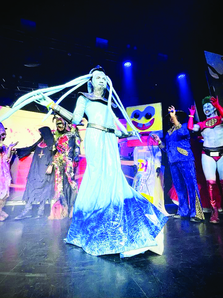 In a Halloween costume, a man looks like an alien with tentacles sprouting from his head and wearing a long skirt around his feet