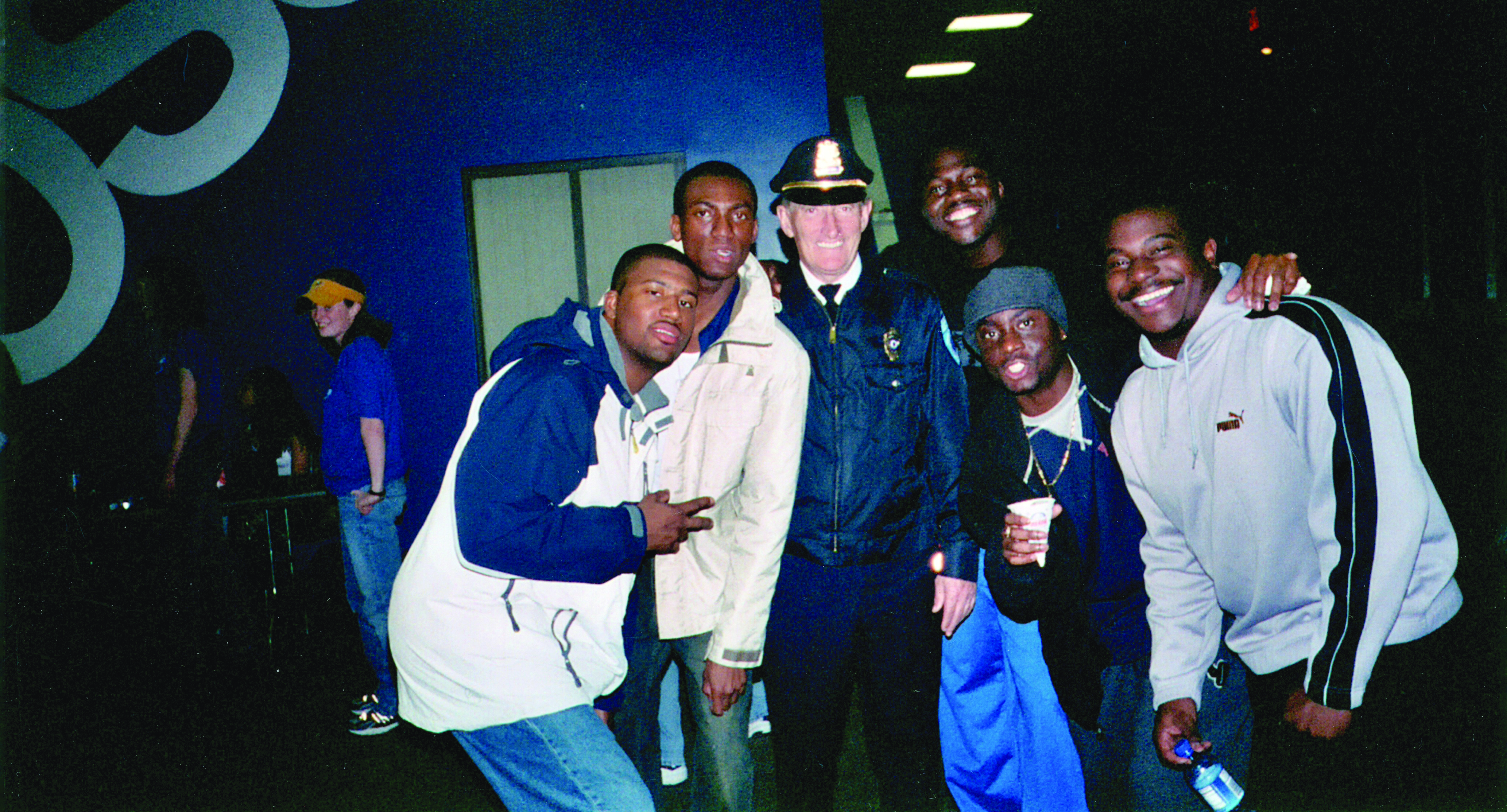 A group of smiling young men standing to the left and right of a police officer