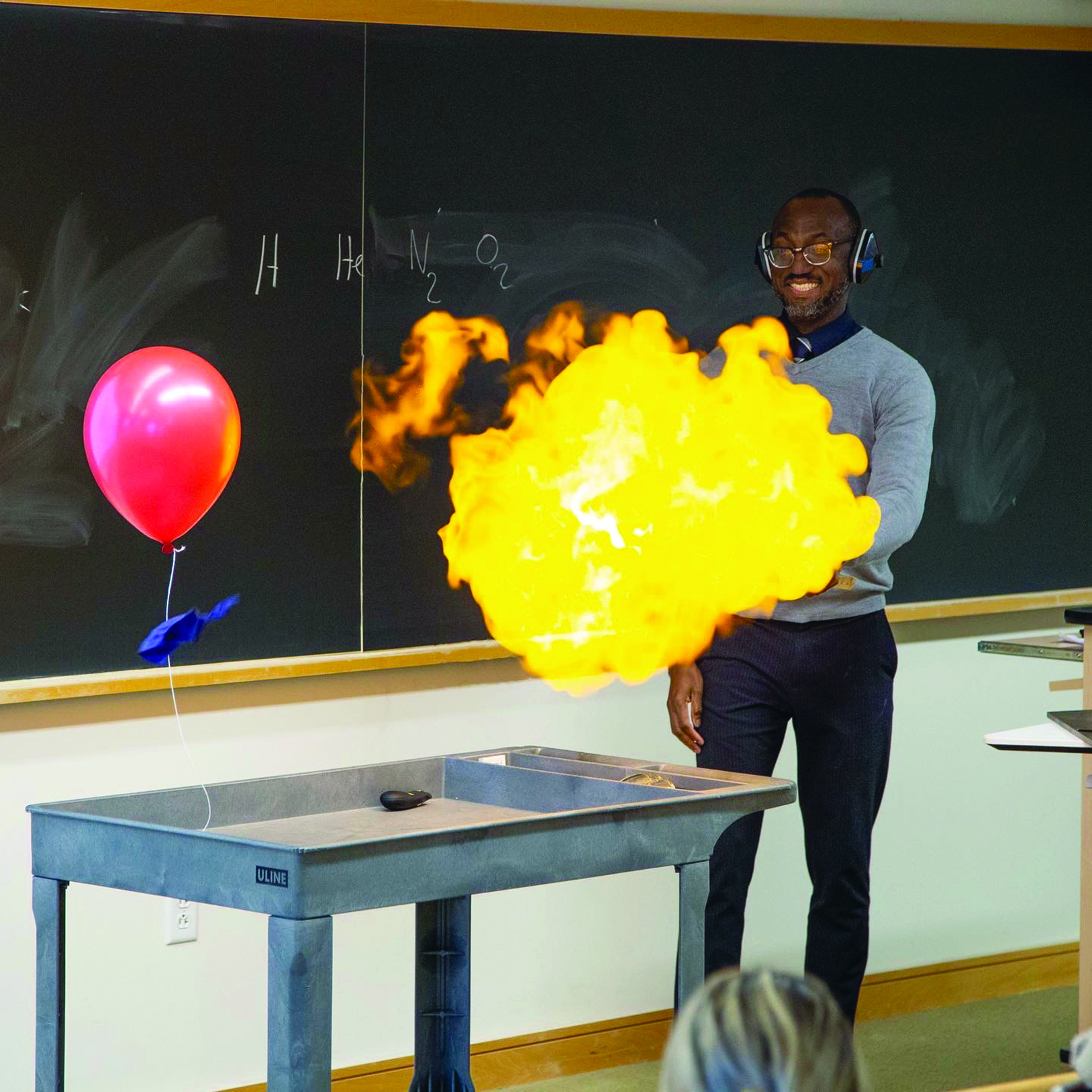 A man performing a chemistry experiment causing a small ball of fire to appear in front of him