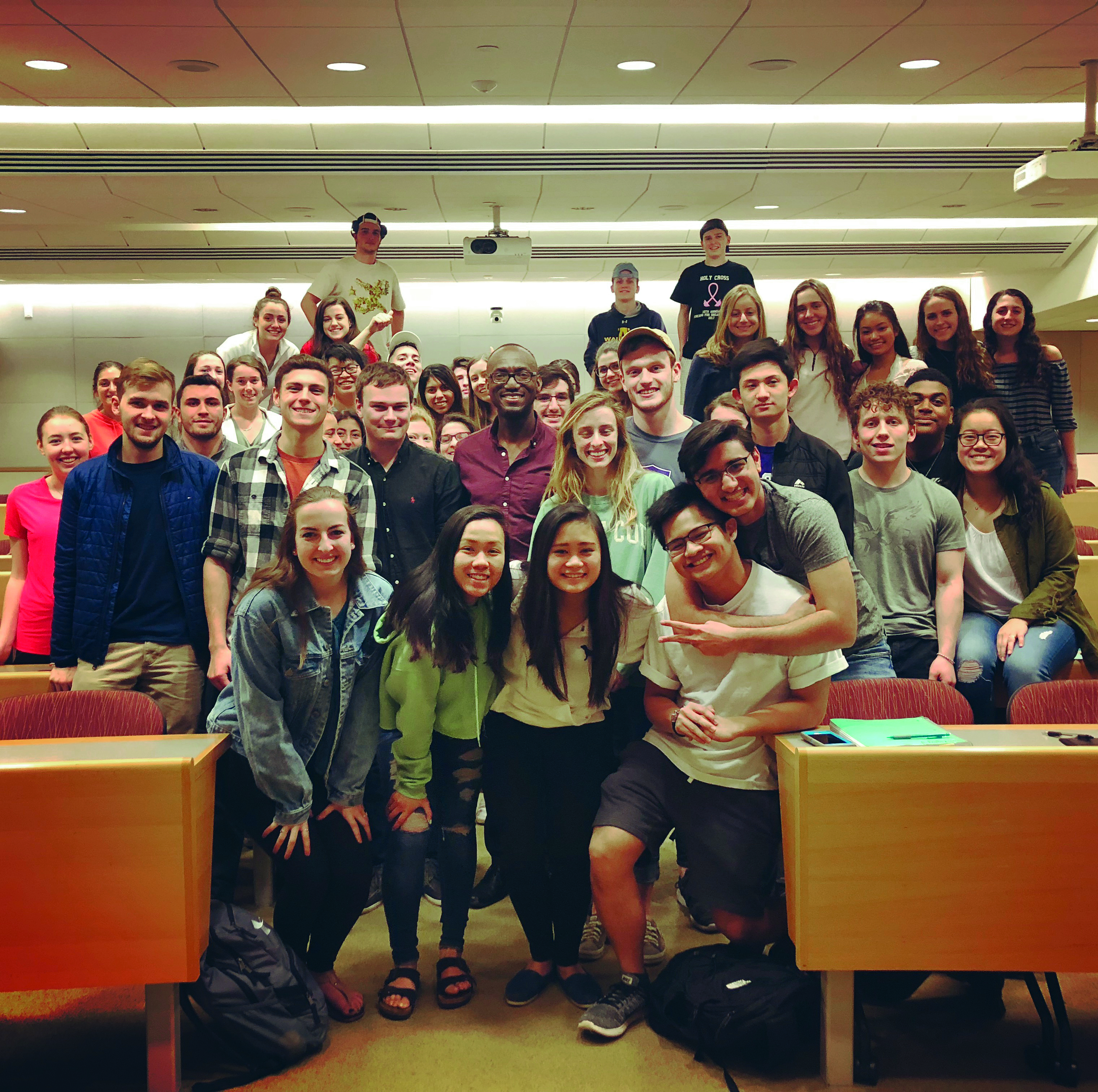 A group of people squeezing together for a photo in a college classroom