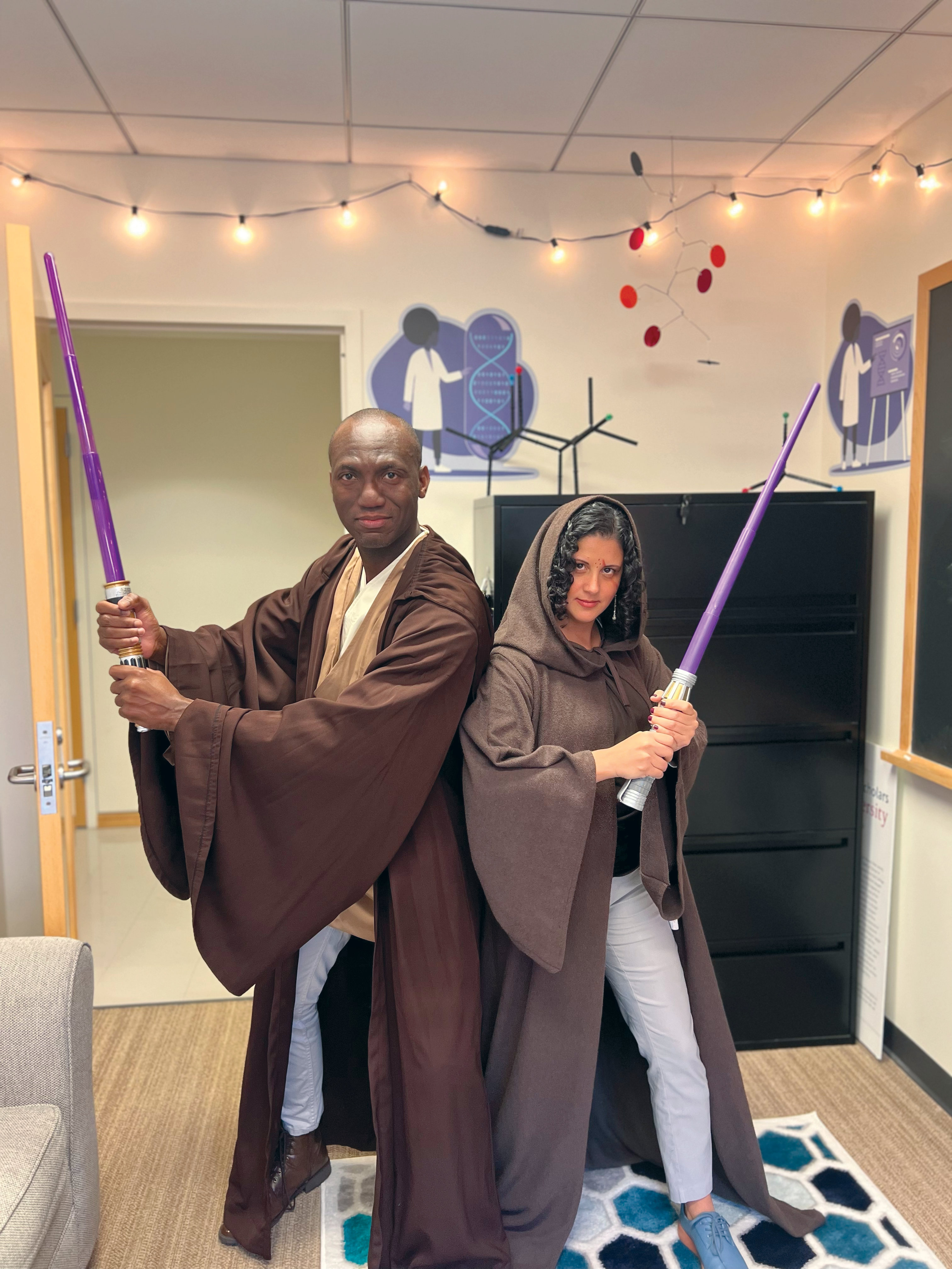 Two people dressed in robes, holding light sabers