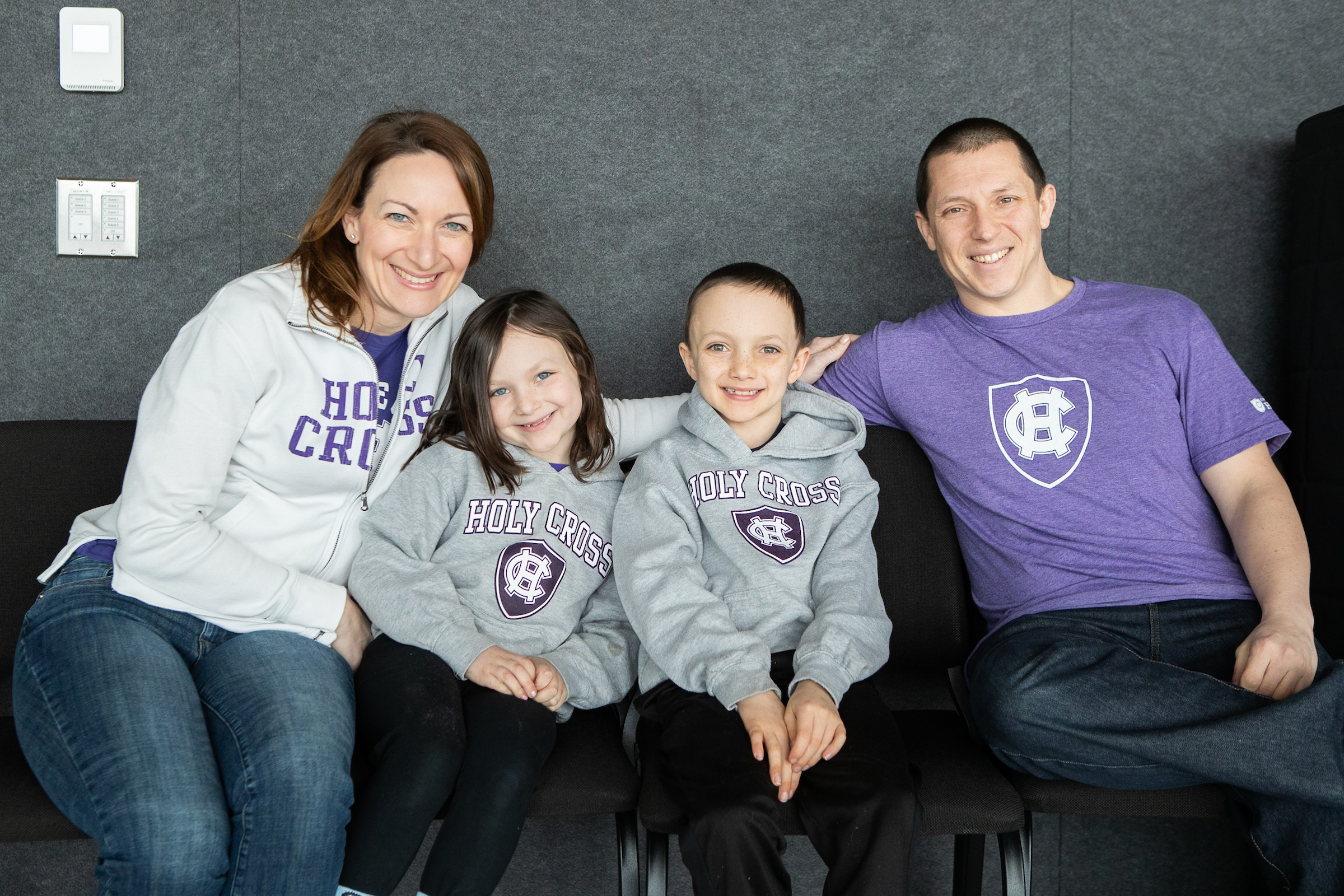 two adults and two children in Holy Cross attire