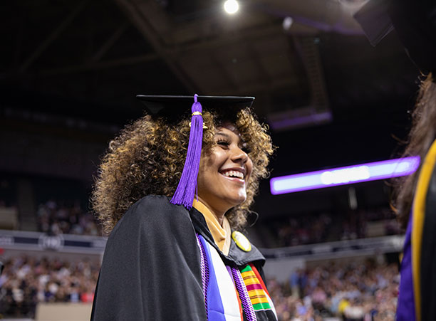 A student excitedly stands in line to receive their diploma.