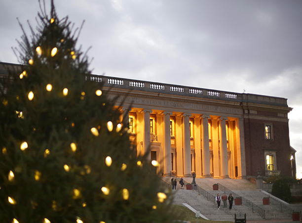 A pine tree sparkles with lights in front of Dinand Library.