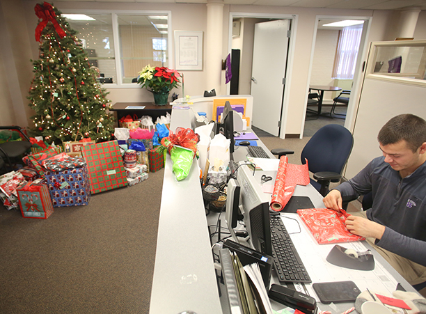 Presents collected for the annual Giving Tree drive surround an adorned tree in Human Resources.