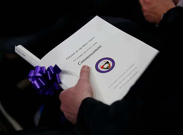 A student holds their diploma alongside the commencement program.