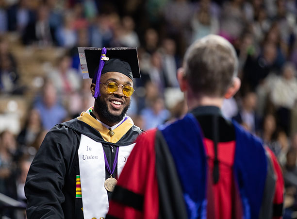 A student smiles as he receives his diploma from Rev. Philip L. Boroughs, S.J., president of the College.