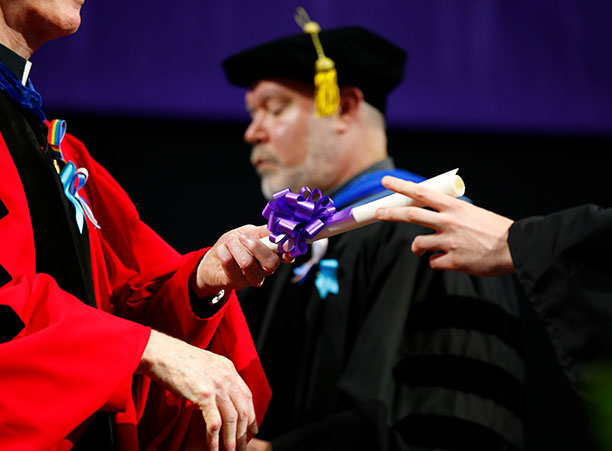 Rev. Philip L. Boroughs, S.J., president of the College, hands a diploma to a student.