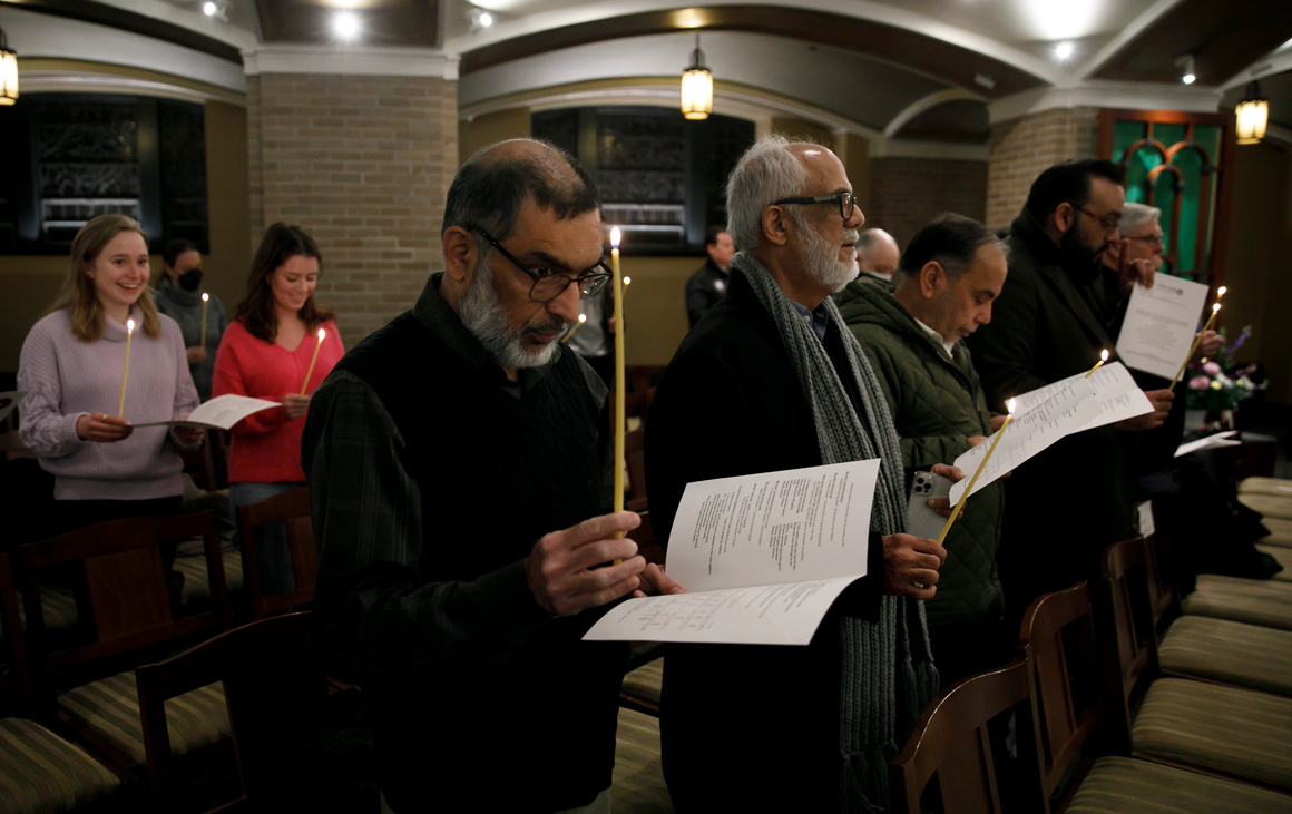 A group of people holding candles sing a song
