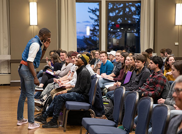 DeRay McKesson stands in the Hogan Ballroom and speaks to a student, who is laughing