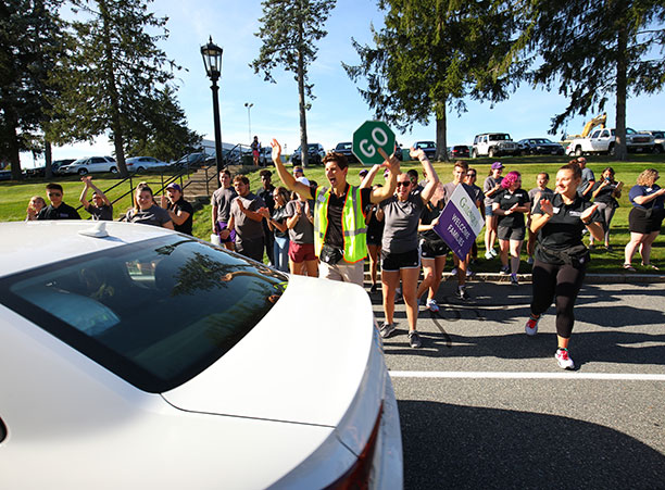 students cheer as a car drives by
