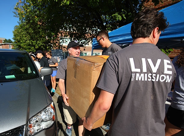 father hayes and a student carry a box