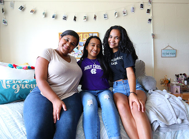 three students sit on a bed