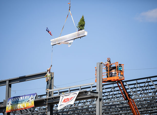 A crane lifts the beam high in the sky