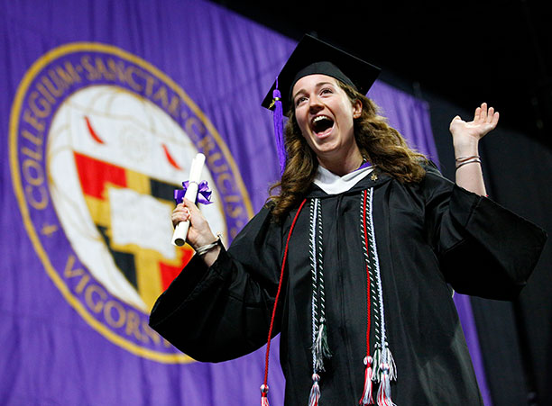 A student celebrates receiving their diploma on stage.