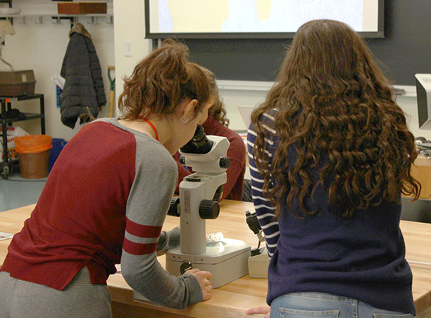 Two high school students look through a microscope during Women in Science Day