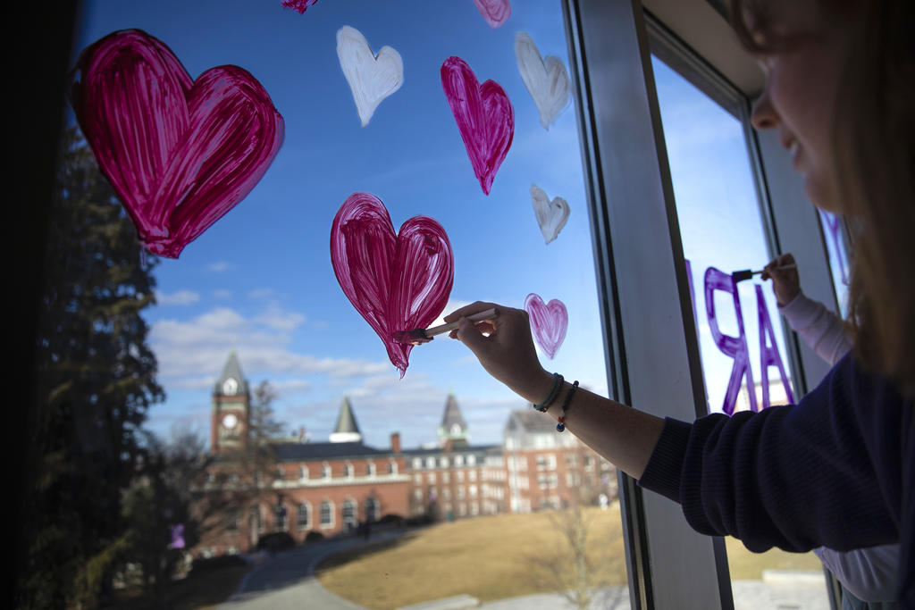 a girl paints hearts on a window