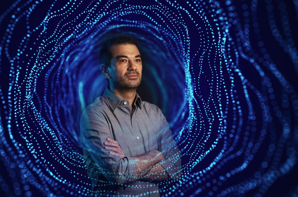 A portrait of a physics professor with a projection of a wormhole overlayed 