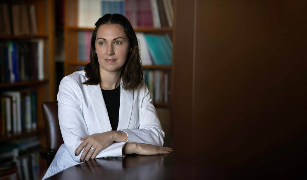 Seated woman in white blazer rests her elbows on a table