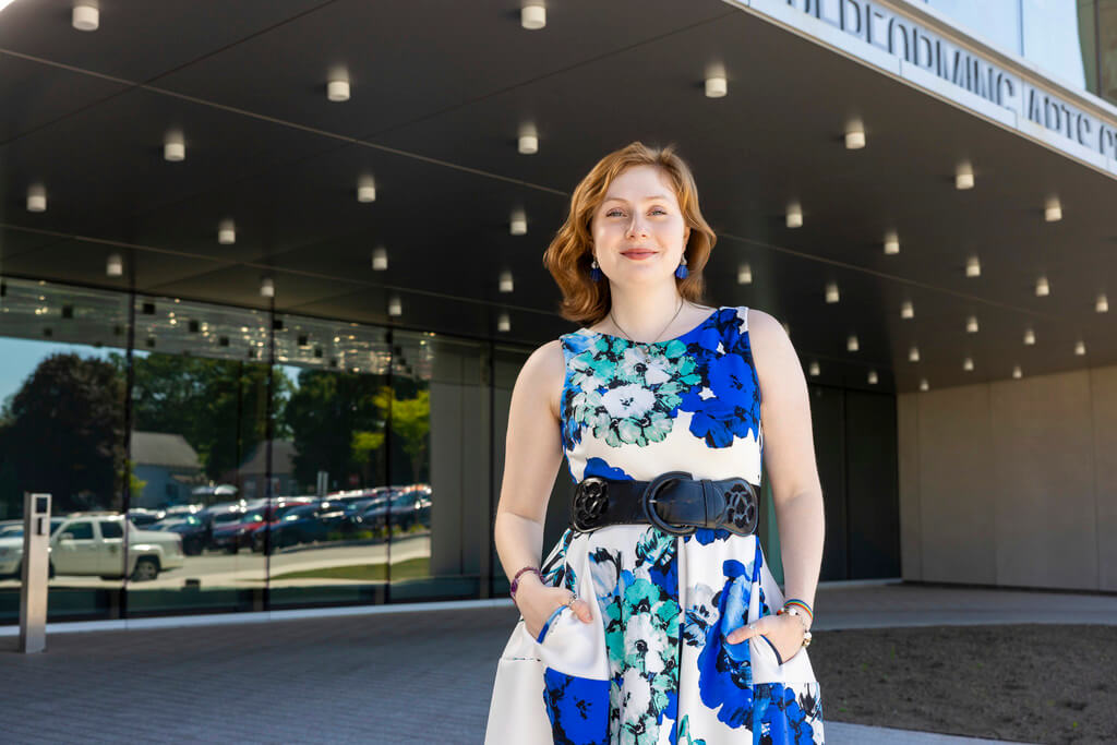 Woman in sleeveless dress stands in front of building