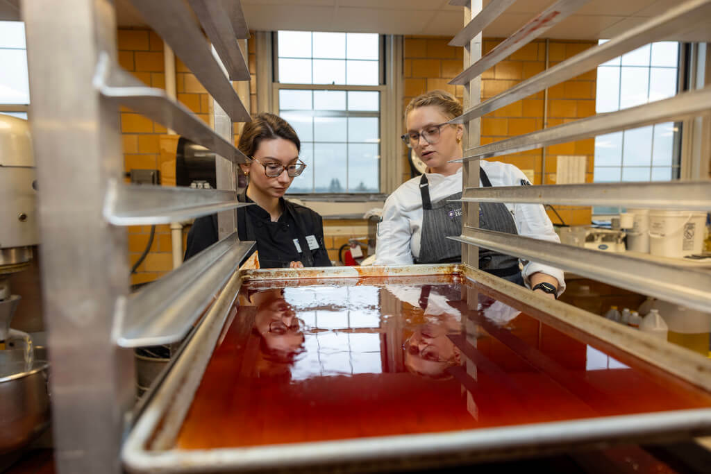 L’Ecoyer and Lucier check on a batch of apple jelly made from 27 pounds of crab apples collected around campus, primarily from Fitton Field, for use in the week’s specialty donut.