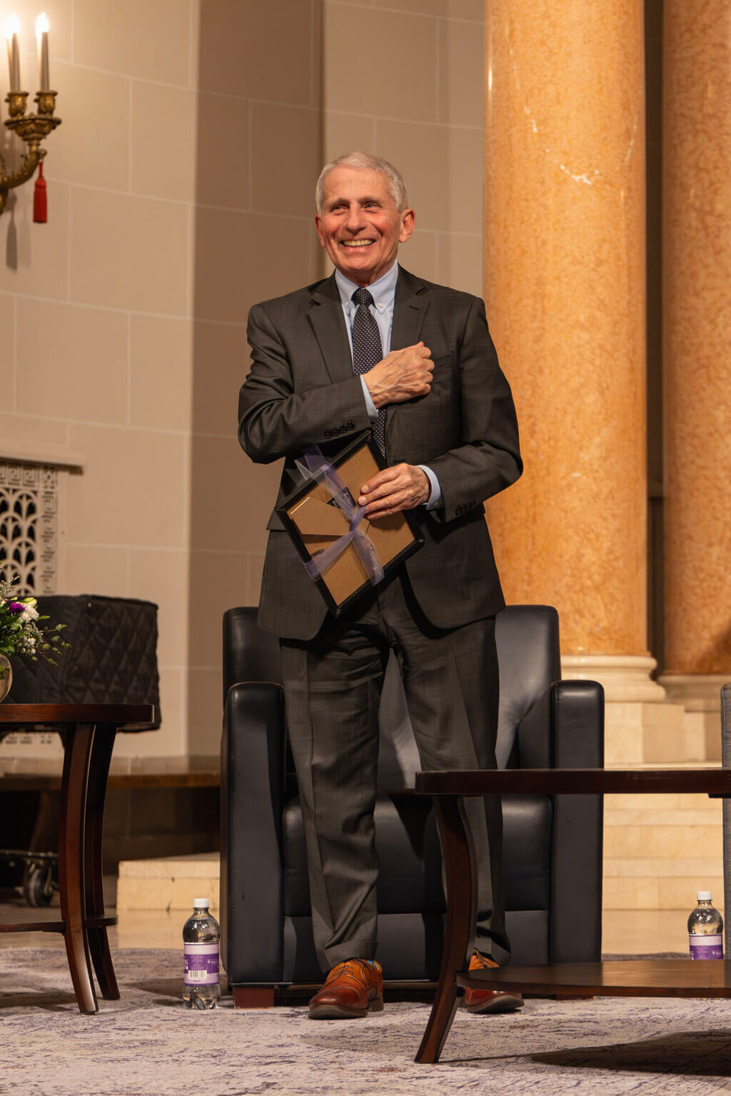 Grey hair man in suit stands with hand over his heart