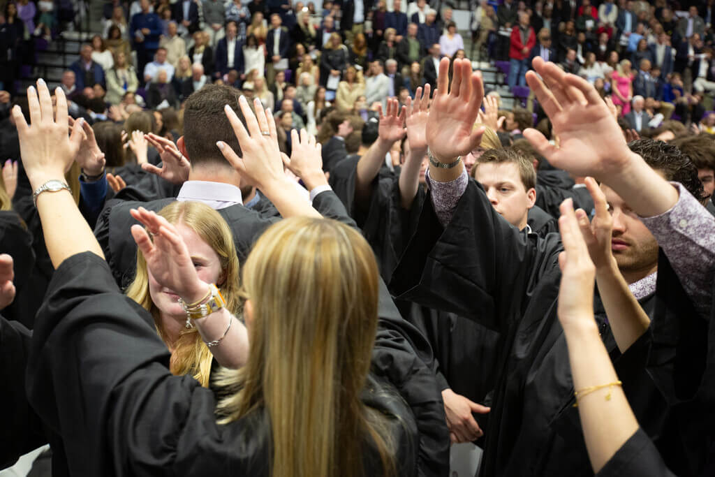 Students with arms raised at 2025 Baccalaureate Mass at the College of the Holy Cross