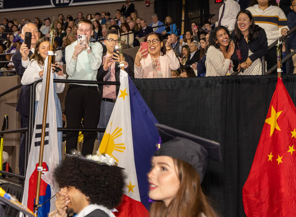 Family members cheer and shoot photos of graduates