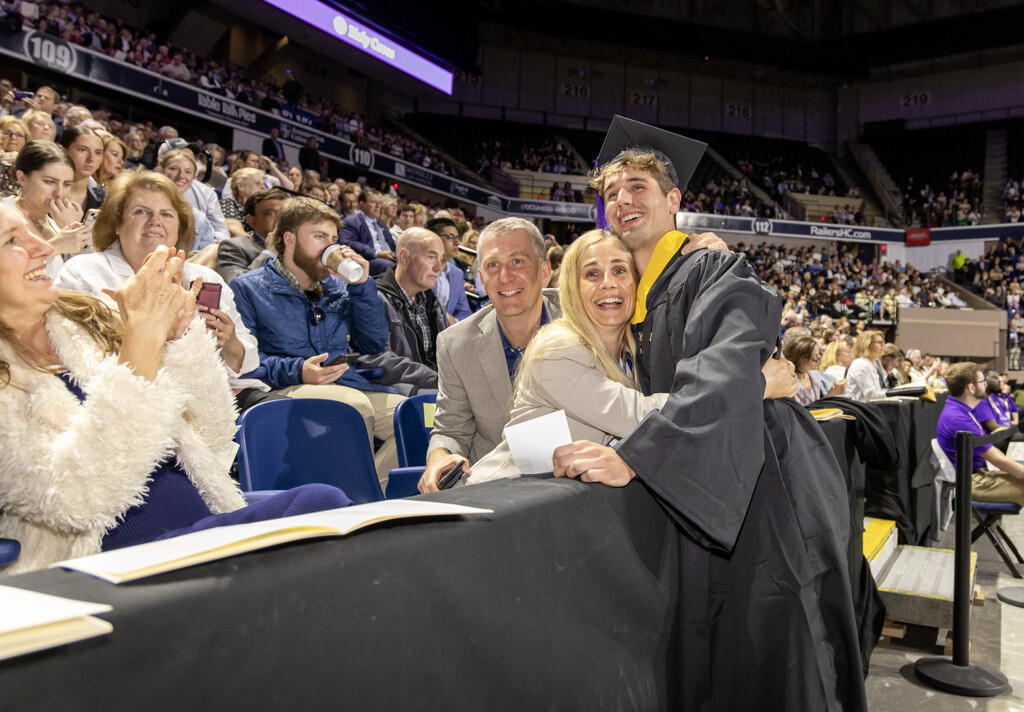 Woman hugs young man in cap and gown