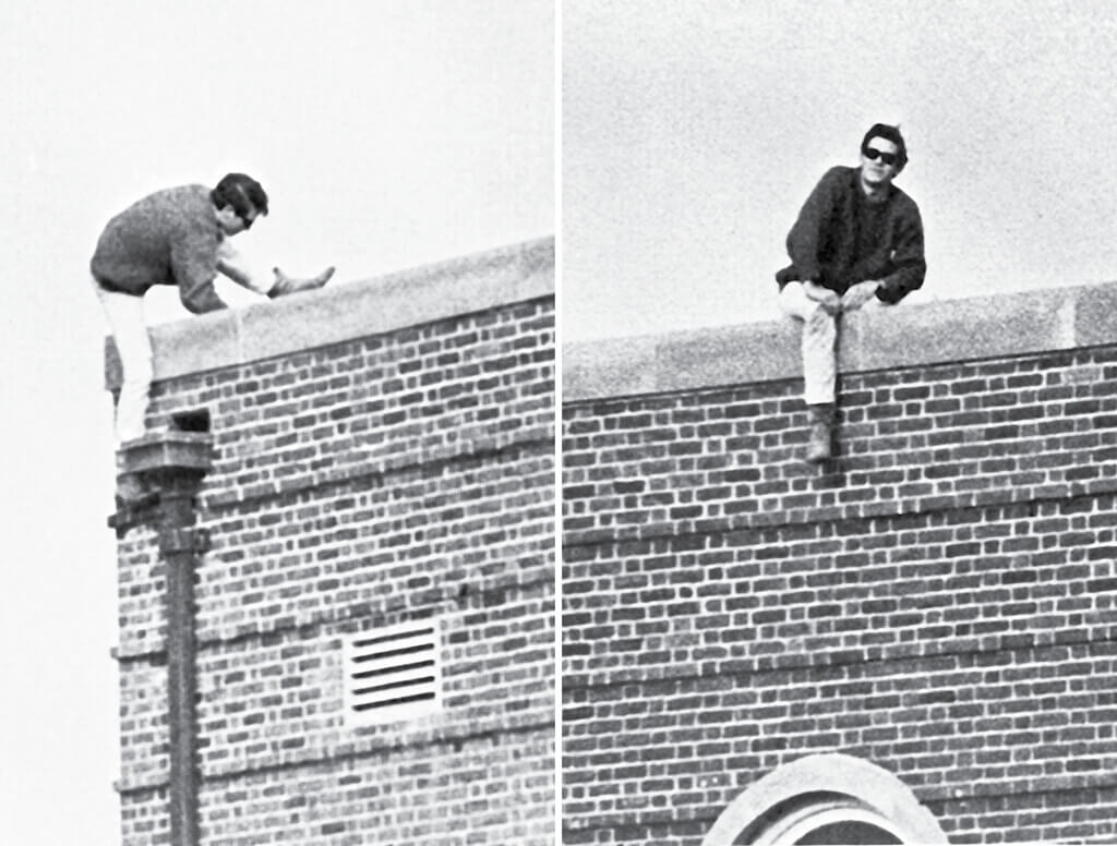 Black and white photo of man sitting atop four story building