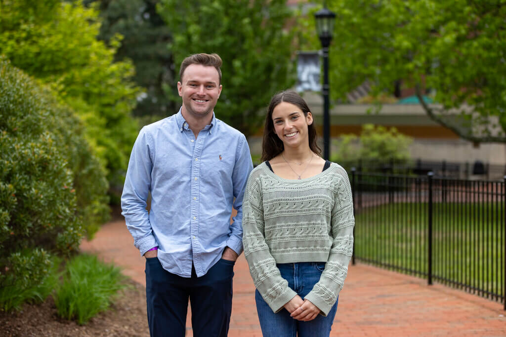 Two standing people smile at the camera