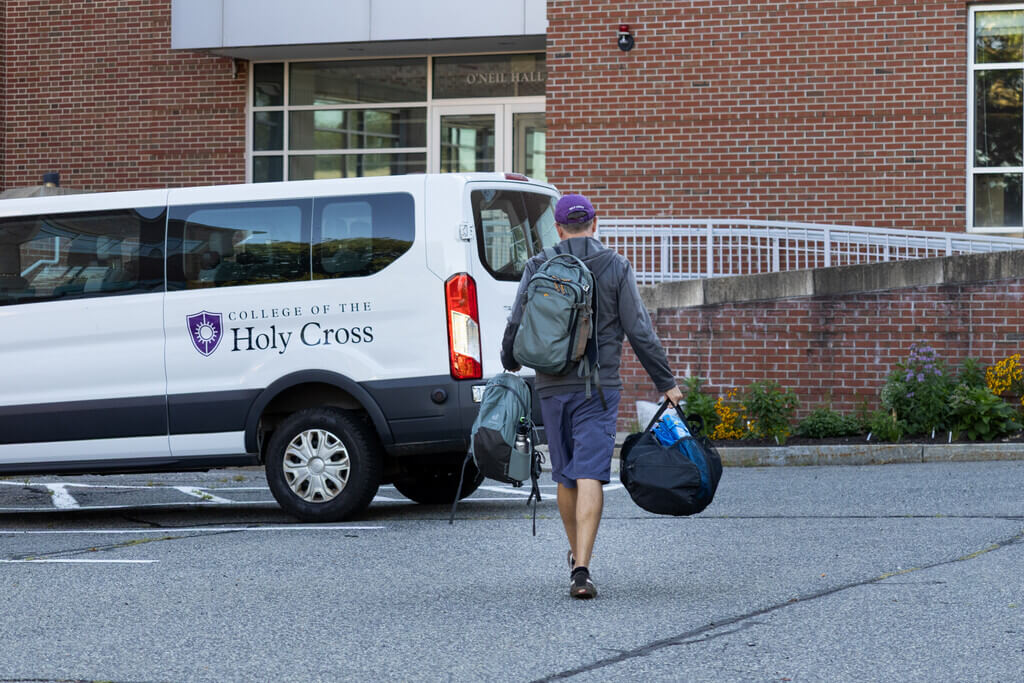 Professor carrying bags to a Holy Cross van