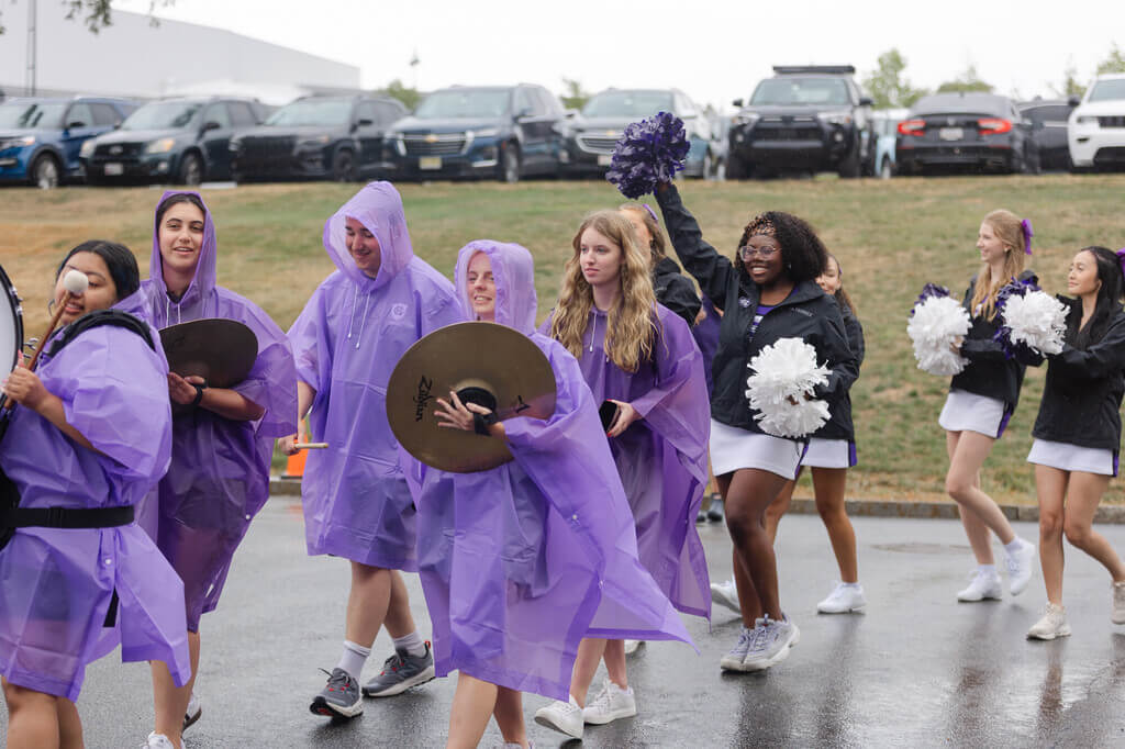 Band members in purple ponchos and cheerleaders