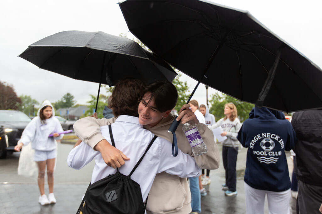 A mother and son hug under umbrellas