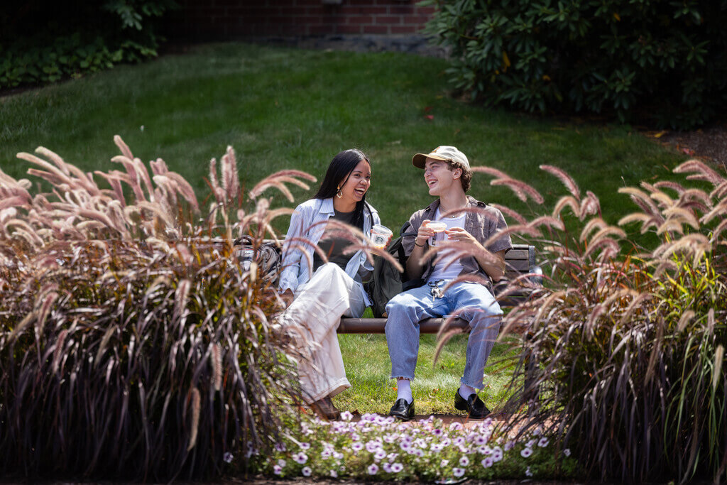 Two students smiling on a bench