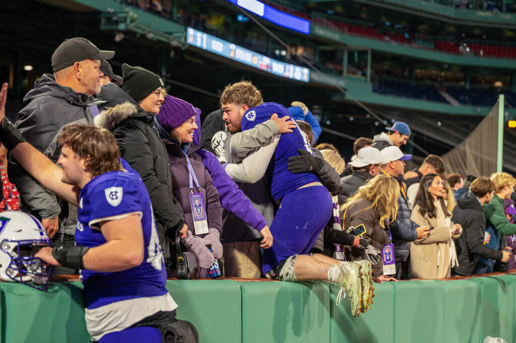 Football players hugging family members in the stands