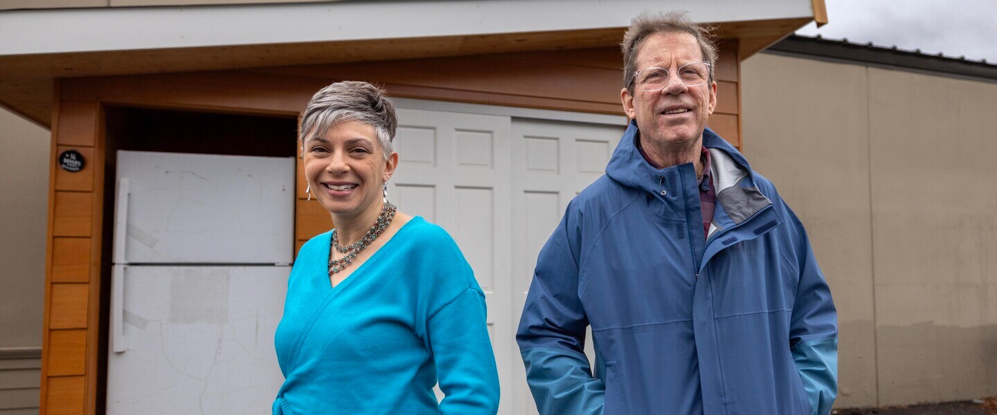 A man and woman stand in front of an outdoor refrigerator