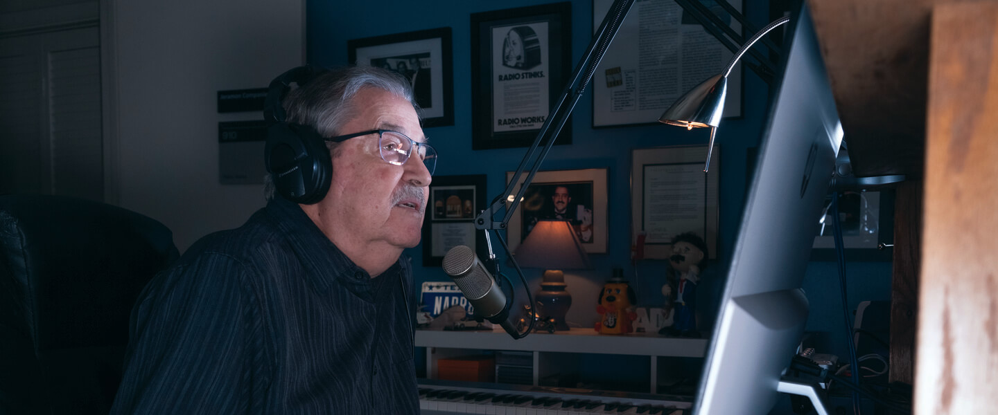 Seated man in glasses speaks into microphone