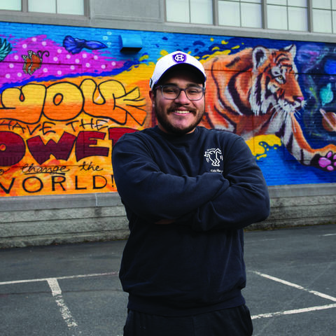 Man stands in front of spray paint mural