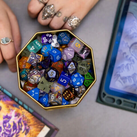 A container of dice sit next to an iPad