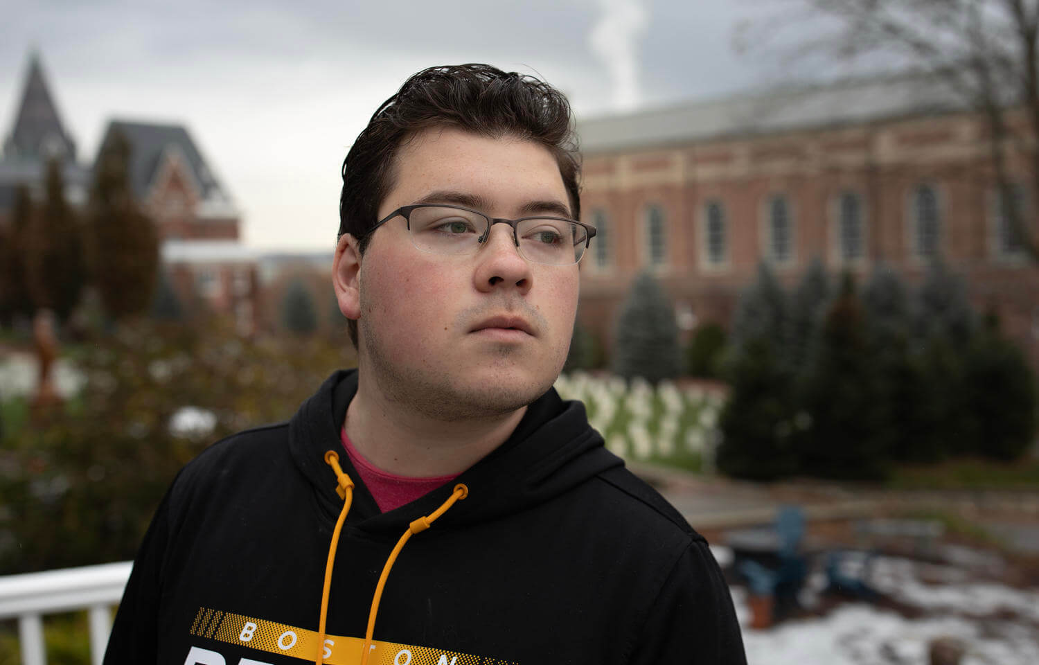 Male student in black sweatshirt looks over his left shoulder. 